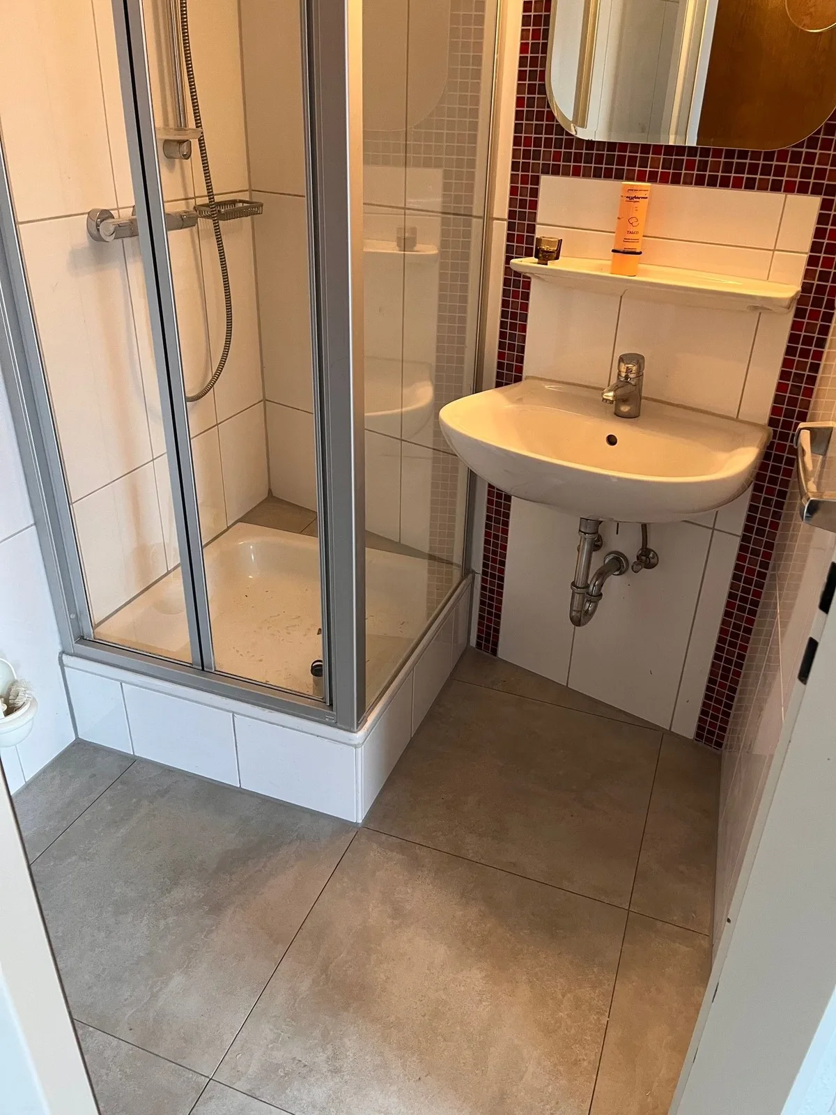 Dasselbe Badezimmer fertig saniert: geflieste Dusche, Waschbecken, neuer Bodenbelag
